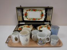 A tray containing commemorative mugs and beakers,