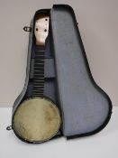A cased four string mini banjo