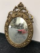 An ornate gilt framed oval mirror