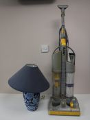 A Dyson DC 3 upright vac cleaner and a pottery table lamp with shade
