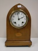 An inlaid mahogany domed topped mantel clock on brass feet
