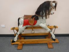 A twentieth century hand painted wooden rocking horse on pine stand with leather saddle