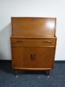 A mid twentieth century teak writing bureau, together with a gilt framed oil on canvas,