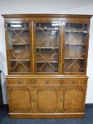 A yew wood triple door bookcase fitted cupboards and drawer beneath