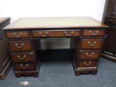 A mahogany twin pedestal writing desk fitted nine drawers with a green leather inset panel