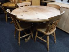 A circular pine pedestal dining table together with four pine fiddle back chairs