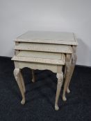 A nest of three glass topped bleached walnut tables