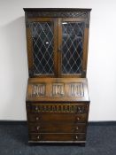 A carved oak bureau bookcase with leaded glass doors