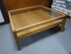 A contemporary glass topped two tier coffee table