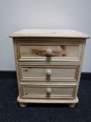 An unfinished pine three drawer bedside chest