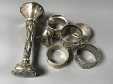 Seven silver items including a small vase, pepperette and five napkin rings.
