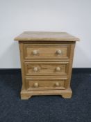 A stripped pine three drawer bedside chest