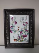 A Chinese porcelain panel in a carved hardwood frame