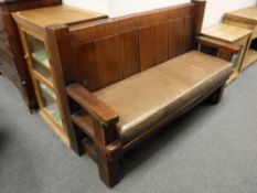 An oak settle with padded leather cushion,