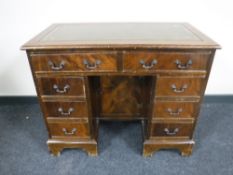 A Georgian style mahogany kneehole writing desk with inset green leather panel