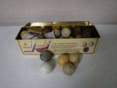 A whiskey tin containing a collection of vintage golf balls