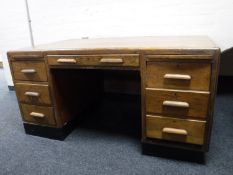 A mid twentieth century oak desk fitted with seven drawers