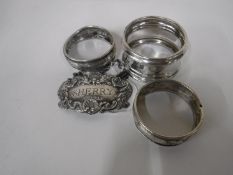 A silver sherry label and three silver napkin rings