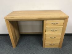 A light oak desk fitted with four drawers,