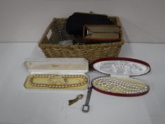 A wicker basket containing costume jewellery, simulated pearls, gents shaving set, compact,