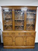 A yew wood triple door bookcase fitted cupboards and drawer beneath