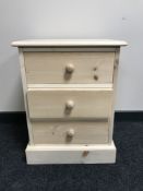 An unfinished pine three drawer bedside chest