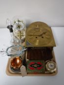A tray containing a brass faced wall clock, clock under shade, liqueur decanter, desk clock,