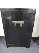 An Oriental lacquered pine double door cabinet