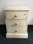 An unfinished pine three drawer bedside chest