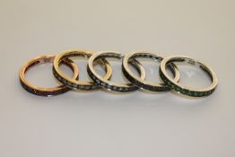 A suite, or stack, of five 9ct gold eternity rings, each set rubies, sapphires, emeralds,