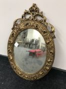 An ornate gilt framed oval mirror