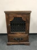 An Eastern hardwood cabinet with ornate metal door,