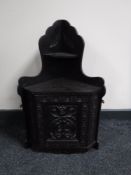 A carved ebonised corner wall cabinet