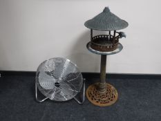 A cast metal garden bird bath and a circular floor fan