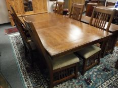 A contemporary arts and crafts style oak extending dining table and six rail backed chairs,