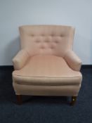 An early 20th century armchair in pink button fabric
