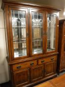 A contemporary arts and crafts style oak triple door display cabinet fitted with drawers and