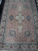 A machine made Persian style fringed rug on pink ground