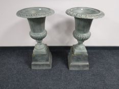 A pair of classical style cast iron urns on stands