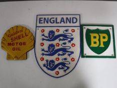 Three cast metal advertising signs, including an England crest,