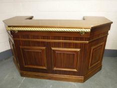 A contemporary mahogany effect bar counter with brass hand rail