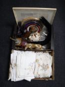 Two boxes containing table linen, wall plates, coffee grinder, figurines, glassware,