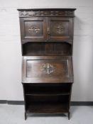 An Edwardian oak bureau with shelves beneath and cupboards above