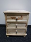 An unfinished pine three drawer bedside chest