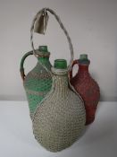 Three antique green glass bottles in wicker covers
