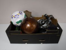 A box containing vintage ice skates, bowling ball, Cine Camera,