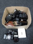 A box containing vintage cameras and accessories, including Minolta, Practika,