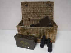 A wicker basket containing five pairs of binoculars and three binocular cases and two metal