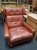 A mid 20th century red button leather wing back armchair