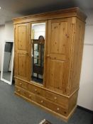 A pine triple door wardrobe fitted five drawers beneath,